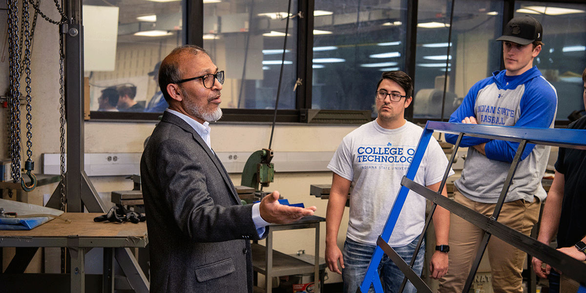  professor speaks to two students in a classroom