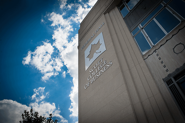 PHOTO OF MULTI STORY BUILDING WITH LARGE INDIANA STATE LEAF LOGO AND TEXT “FEDERAL HALL” AND “SCOTT COLLEGE OF BUSINESS” WITH BLUE SKY IN THE BACKGROUND