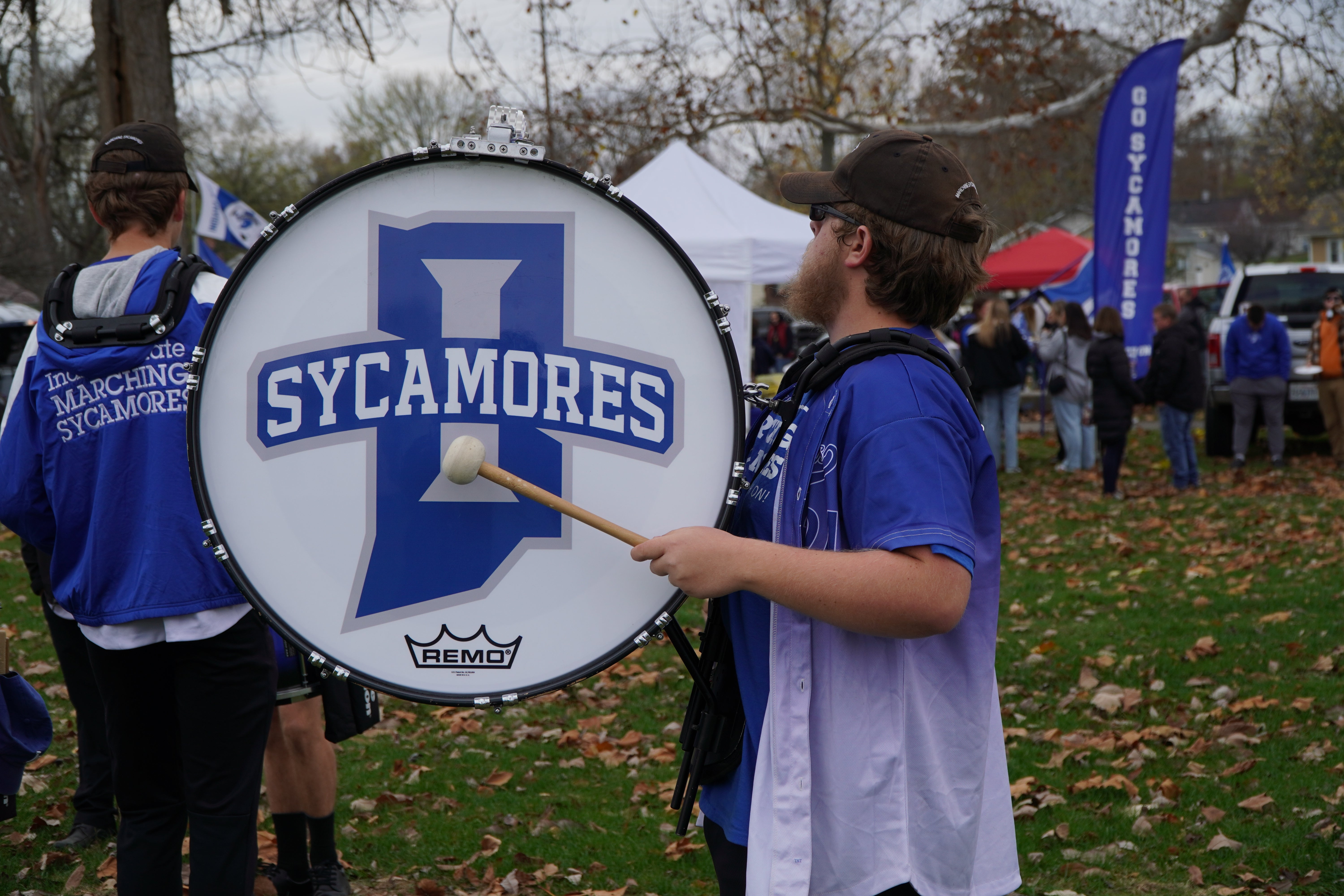 A Sycamore Marching drummer playing a huge drum with the Indiana State Sycamres logo on the drum.