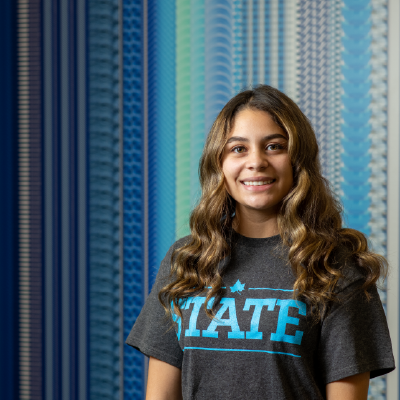 Student standing in front of a blue patterned wall